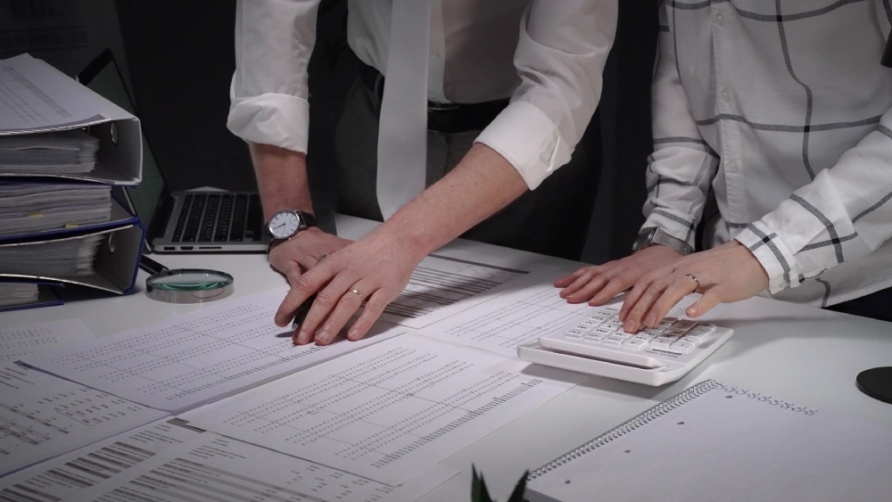 Forensic review of financial records with magnifying glass and calculator